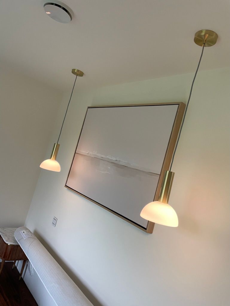 Two bedside pendant lights suspended beside a rectangular wall mirror